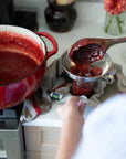 The canning funnel in use for canning jam in a kitchen.