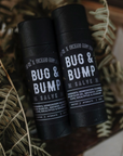 Two black tubes of Bug & Bump Salve are placed on small ferns.
