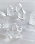 Six quartz crystals stand on a white surface. 