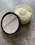 An open container of cocoa rose facial cream on a gray surface.