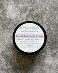 A tub of Cocoa Rose Facial Cream placed on a gray surface