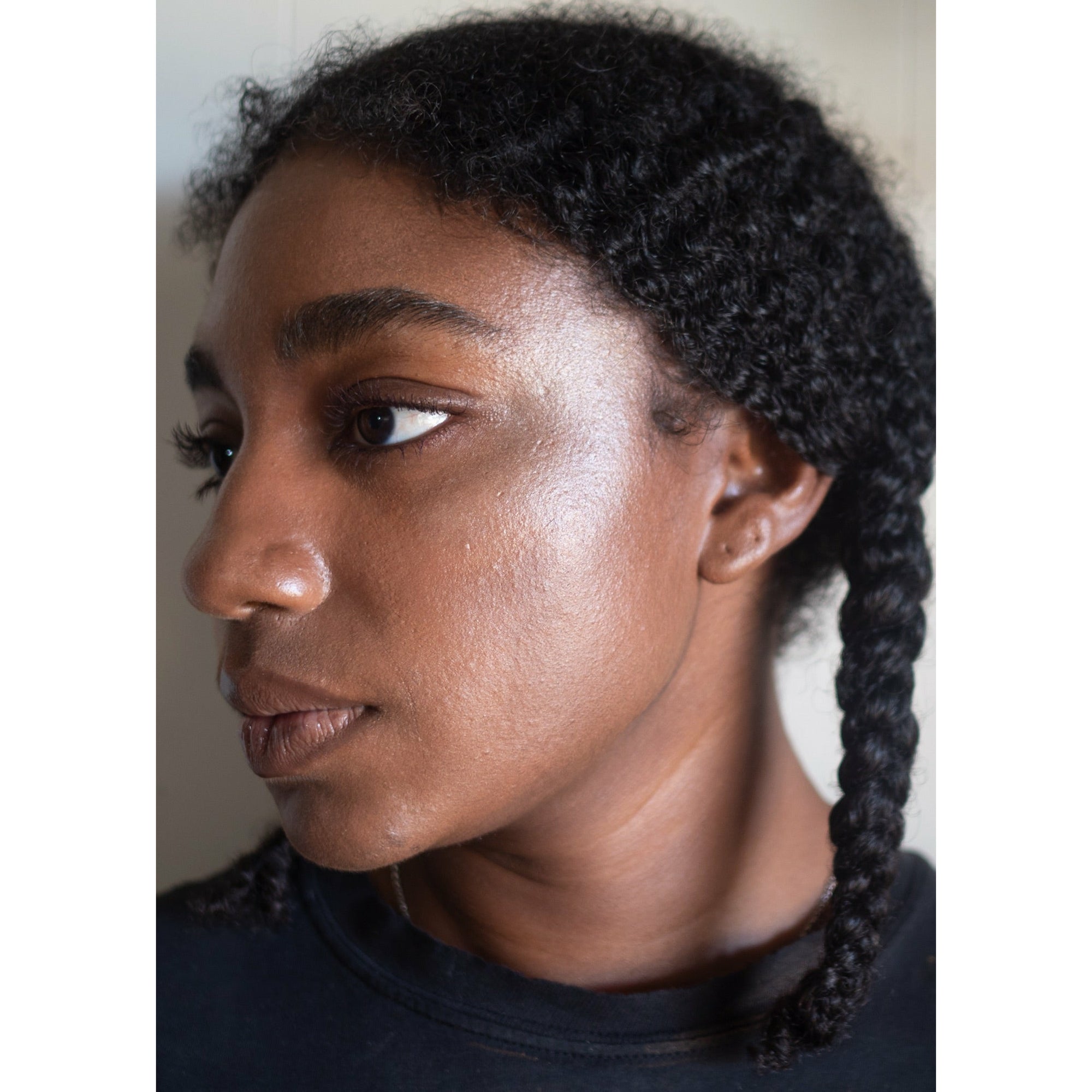 Woman's profile with beam face highlighter applied on cheekbone