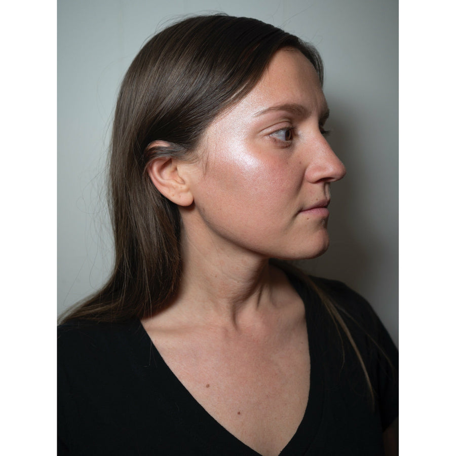 Womans profile with beam face highlighter applied on cheekbone
