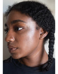 Woman's profile with beam face highlighter applied on cheekbone