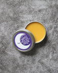 Open container of yellow Babies Moon Salve on gray background