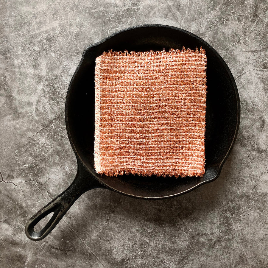 A copper cleaning cloth in a cast iron pan