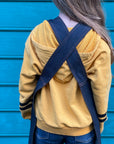 A child facing away from the camera wears the denim child's apron. The back of the apron is displayed. 