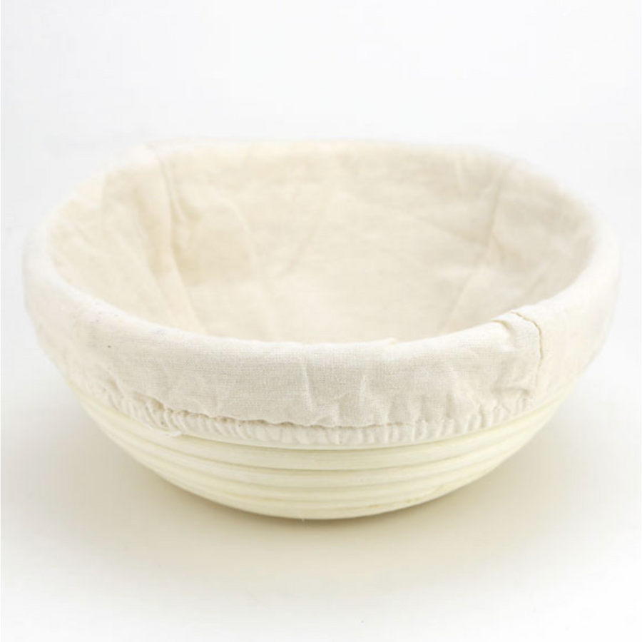 A bread proofing basket with a muslin liners sits with a white background.