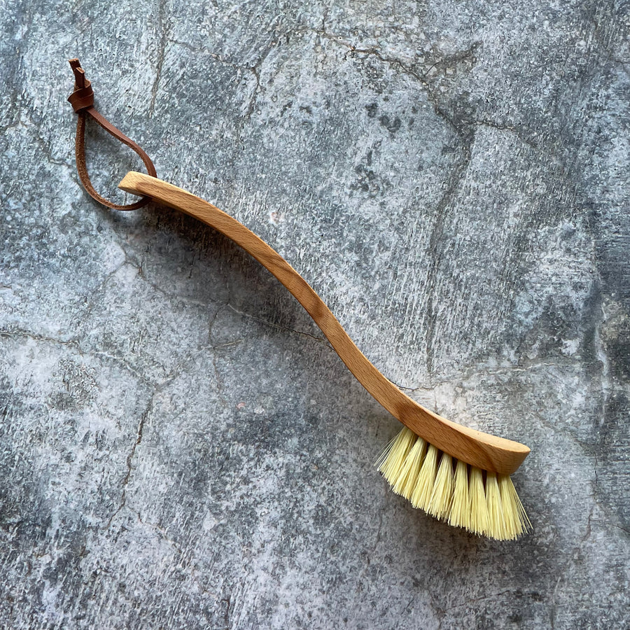 Profile of wooden dish brush in front of grey background