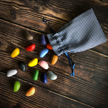A cloth satchel of crayon rocks is opened on a wooden surface. 
