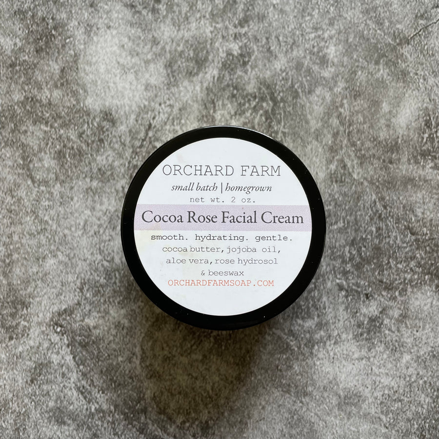 A tub of Cocoa Rose Facial Cream placed on a gray surface 